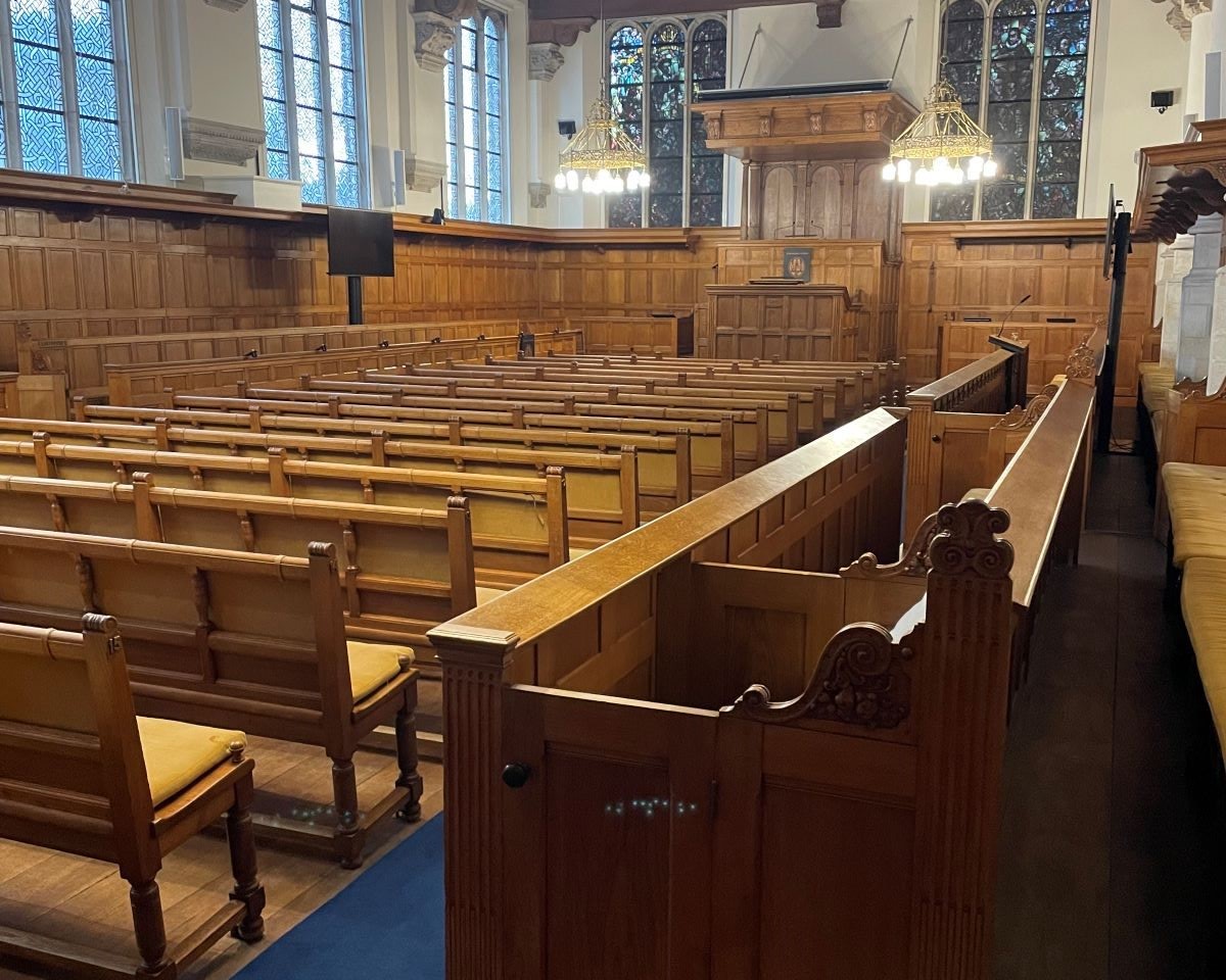 Interior of old building with rows of wooden pews