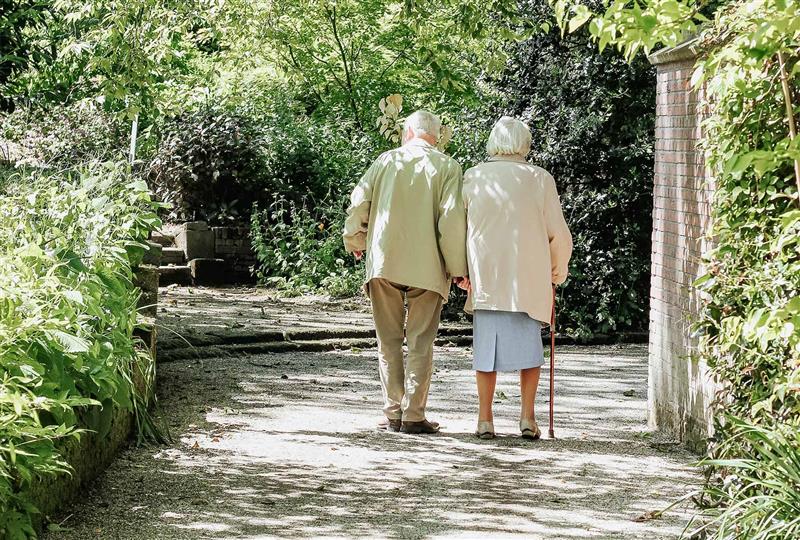 An elderly couple walking in the sunshine