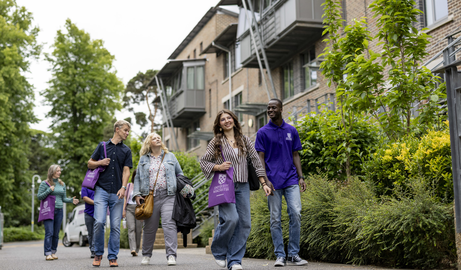 A student walks a group of visitors through a student village