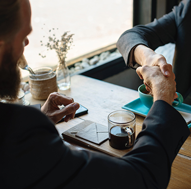 People sitting at a table shaking hands