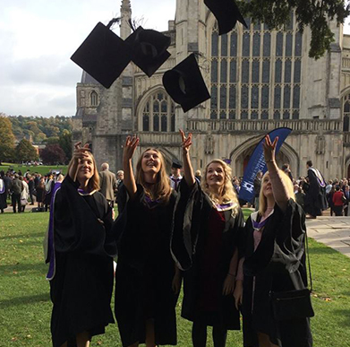 Students outside of the Cathedral at Graduation throwing their mortar boards into the air