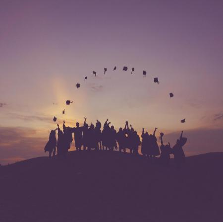 student silhouettes at graduation against a sunset
