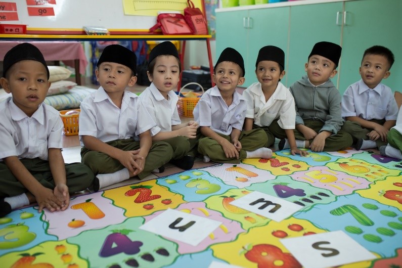 Seven young children sitting in a classroom