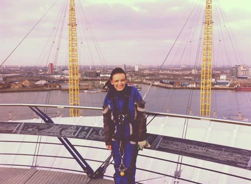 A woman in climbing clothes standing on top of a building