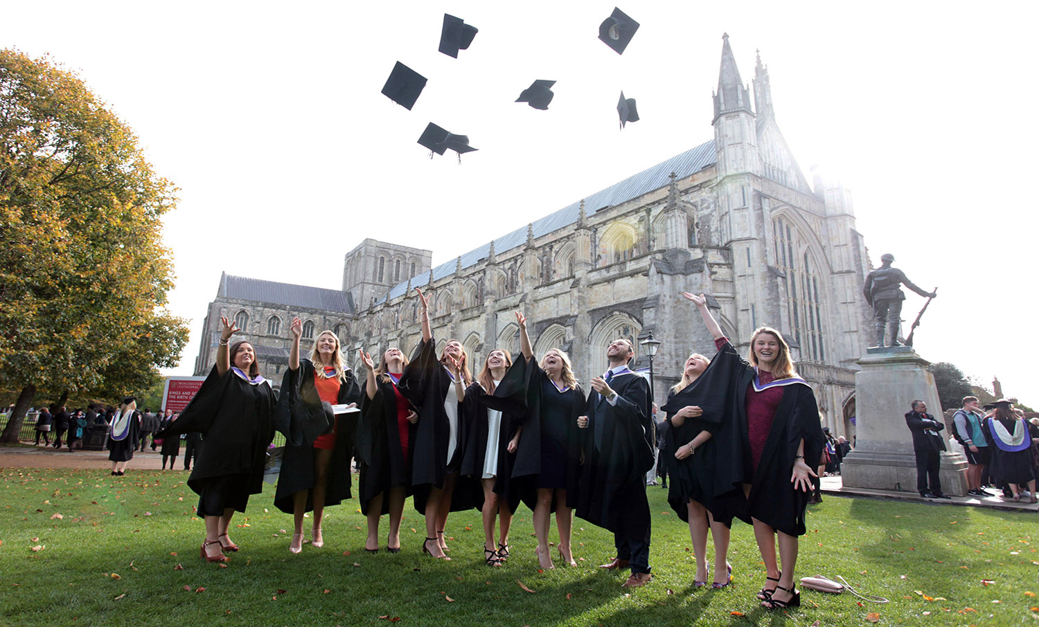 Graduates throwing caps in the air outside Winchester Cathedral