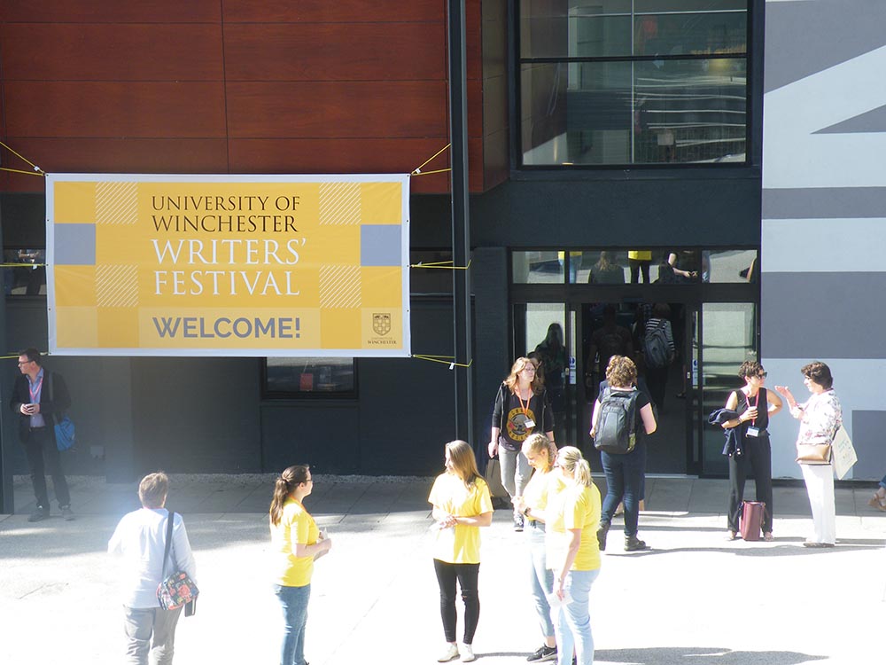 Birds eye view of people mingling around a plaza in front of a modern building