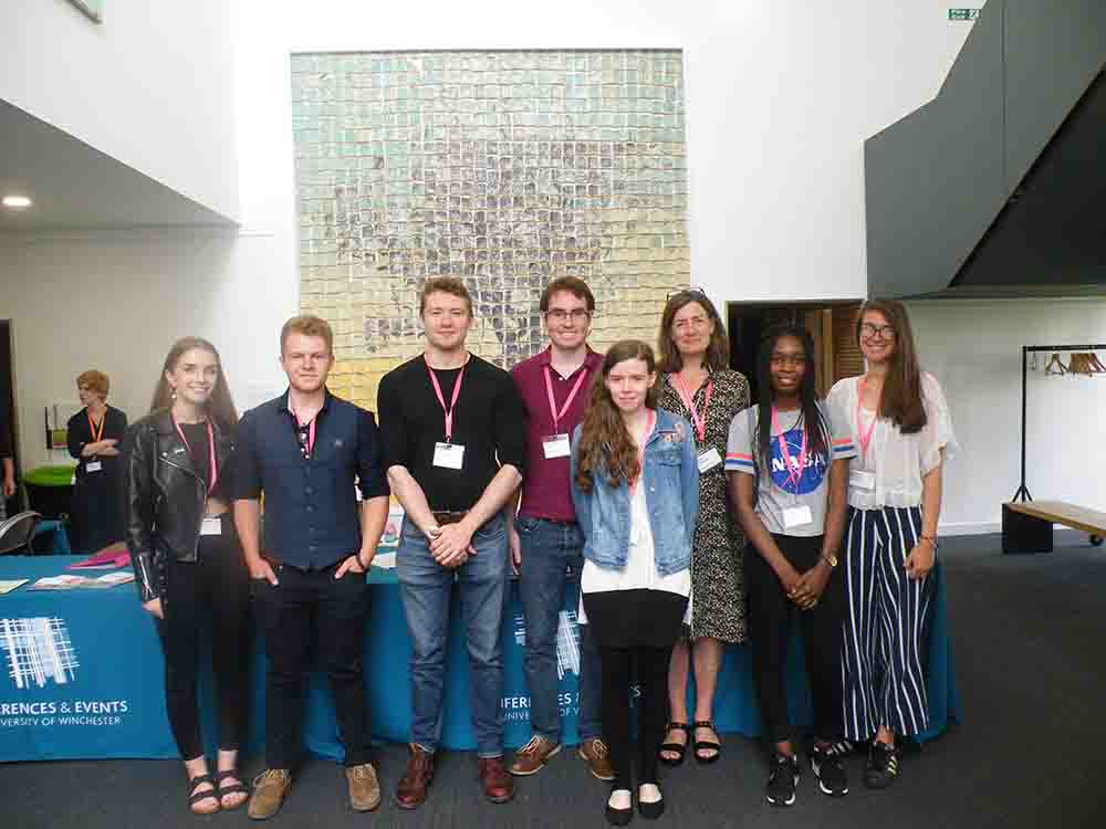 Group of eight young festival scholars pose together inside the Stripe auditorium