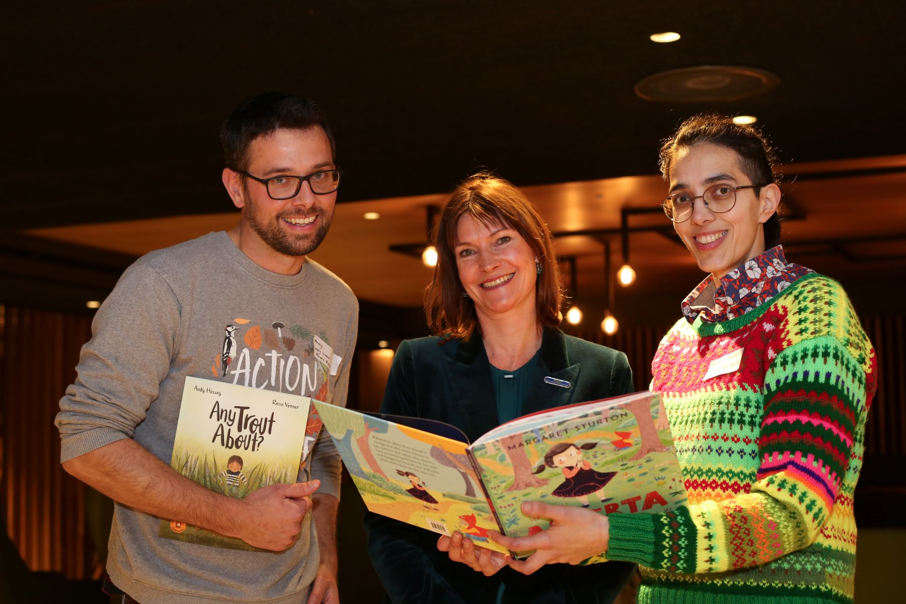 A man and two women looking at children's picture books