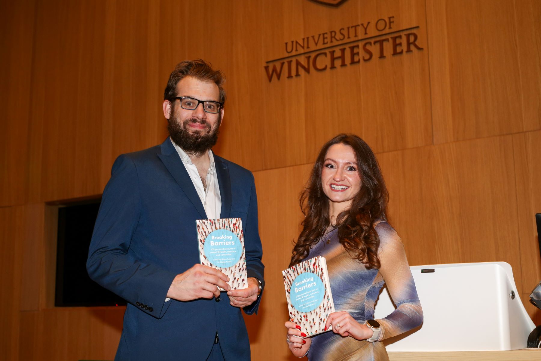A bearded man and young woman holding up books
