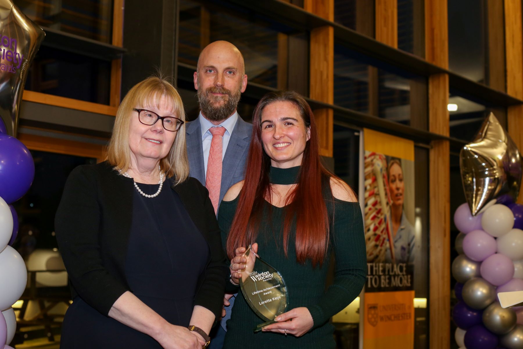 Two women and man with glass trophy