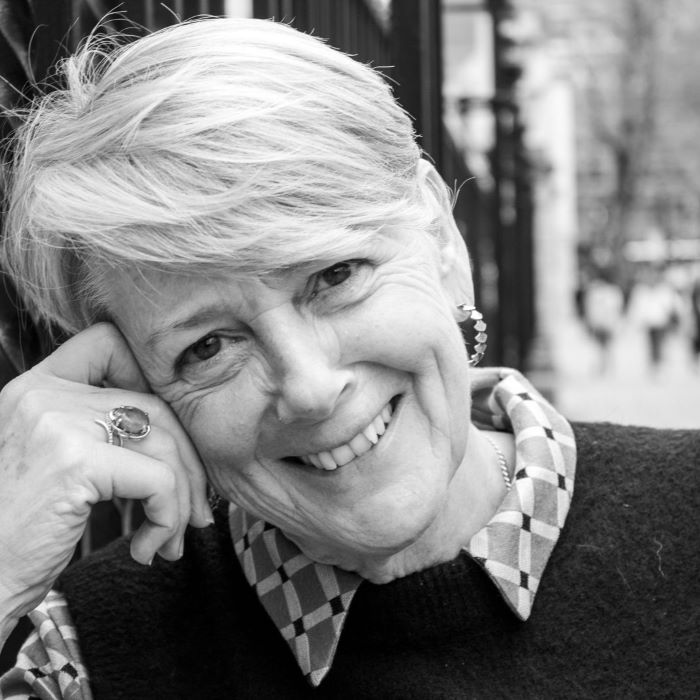 black and white photo of smiling middle aged woman with her head rested on her hand