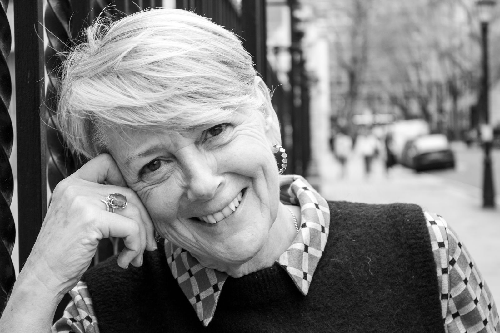 black and white photo of smiling middle aged woman with her head rested on her hand