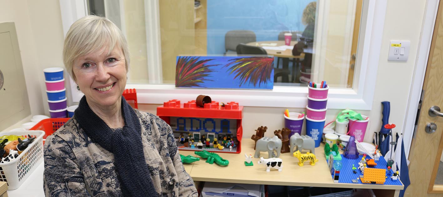 Alison James seated in front of table of Lego models