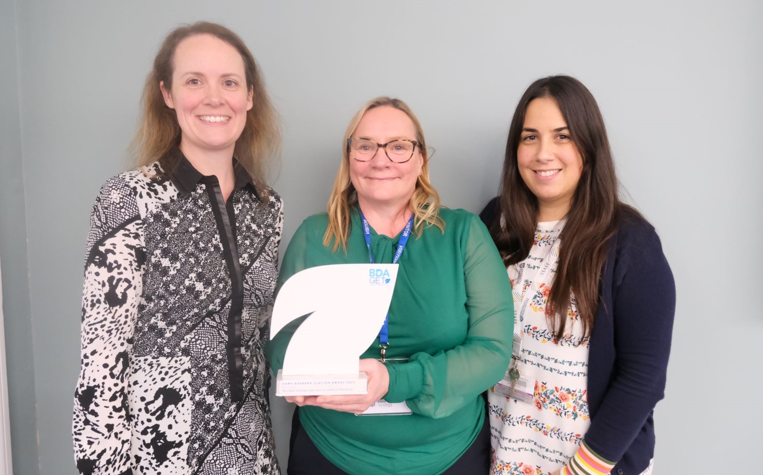 Three women. Centre woman holds white trophy