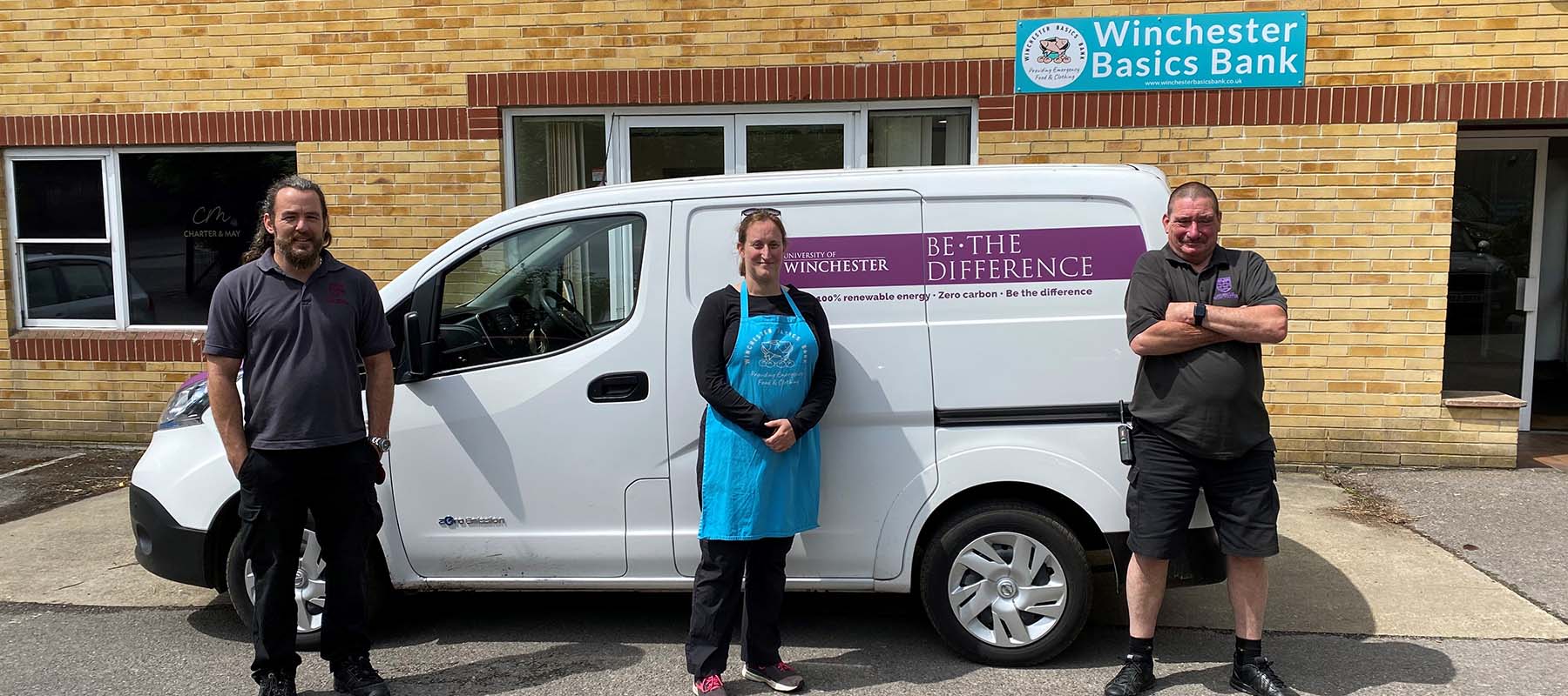 Three people standing in front of University branded van outside the Winchester Basics Bank