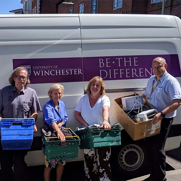 Three people standing in front of University branded van outside the Winchester Basics Bank