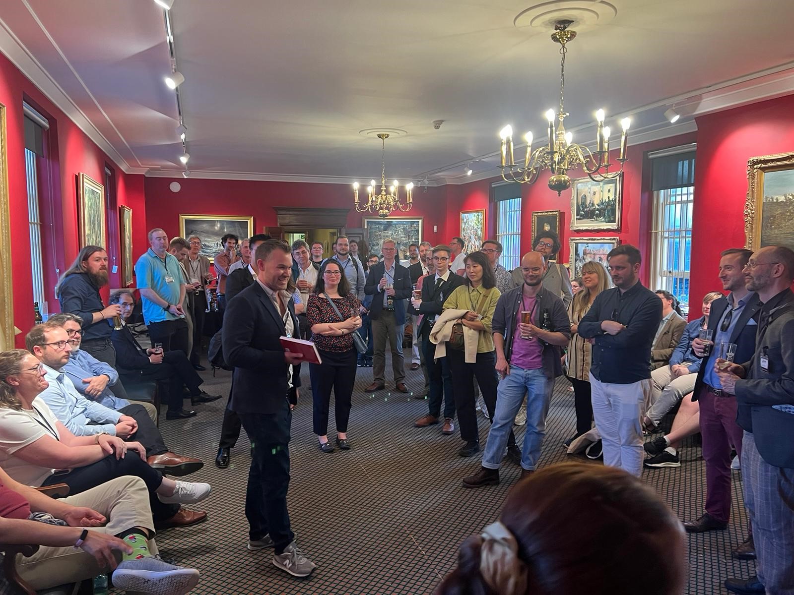 People at drinks reception in a room with red walls