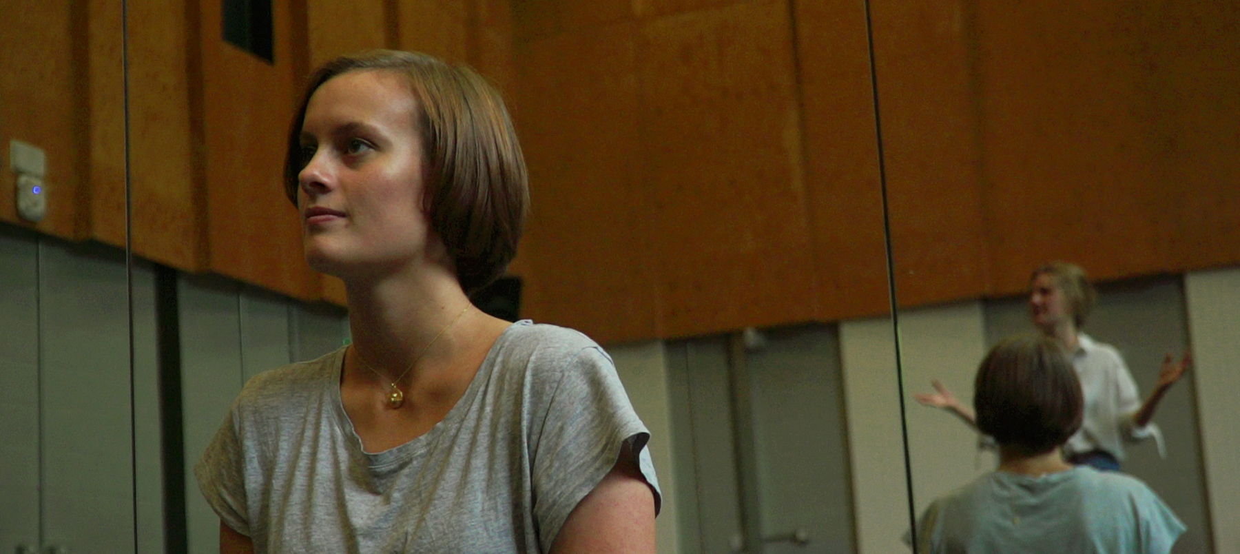 Young woman in grey t-shirt sitting in rehearsal room