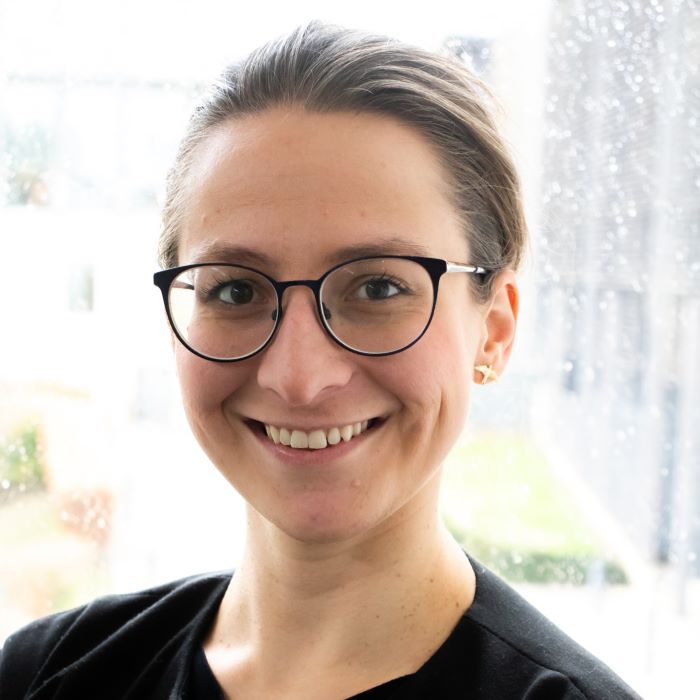 Woman with dark hair tied back, wearing glasses