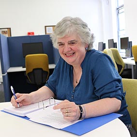 Claire Gradidge sitting at a desk with her book manuscript