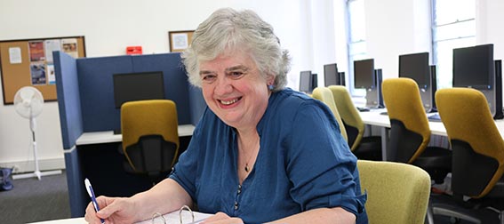 Claire Gradidge sitting at a desk with her book manuscript