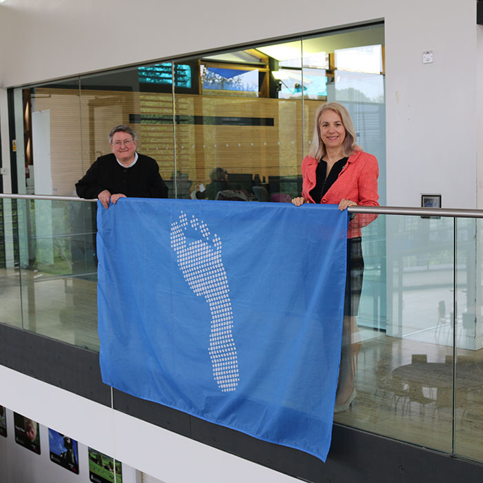 Joy Carter and Liz Stuart holding the blue footprint flag
