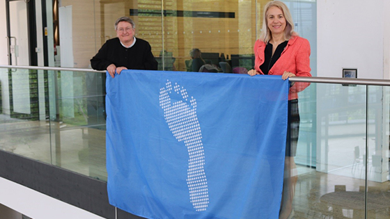 Joy Carter and Liz Stuart holding the blue footprint flag