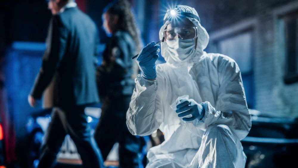 Forensic investigator in overalls and mask wearing a blue headtorch