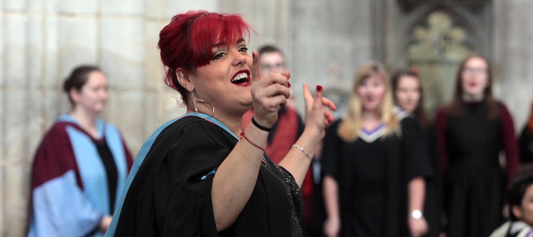 Hannah in academic gown conducting choir