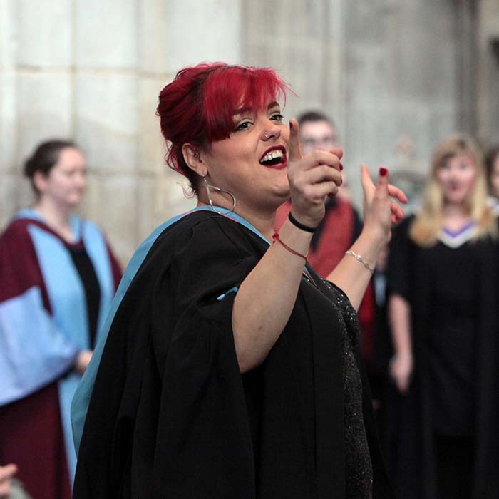 Hannah in academic gown conducting choir