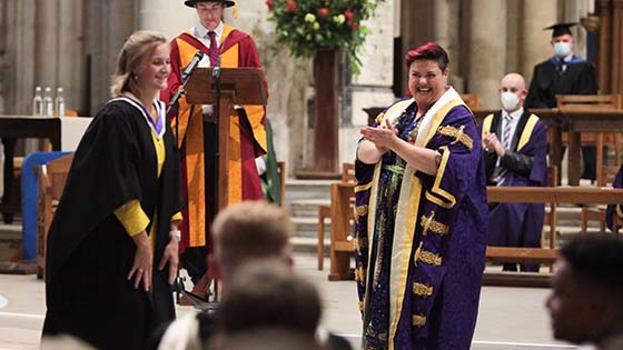 hannah williams in graduation robes greeting a student during a graduation ceremony