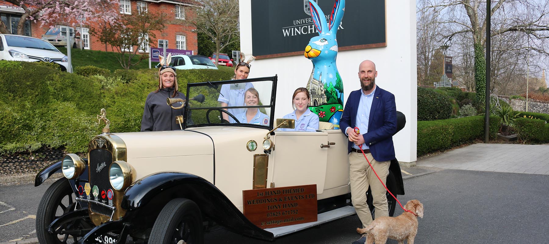 Giant hare sculpture in back of vontage car with group of people