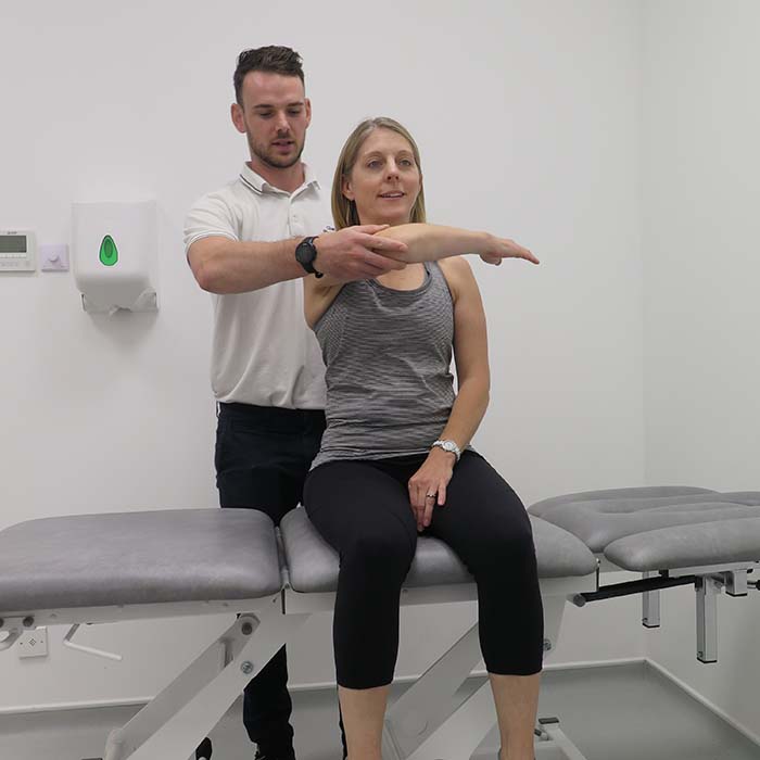 Physiotherapist holds arm of woman sitting on couch