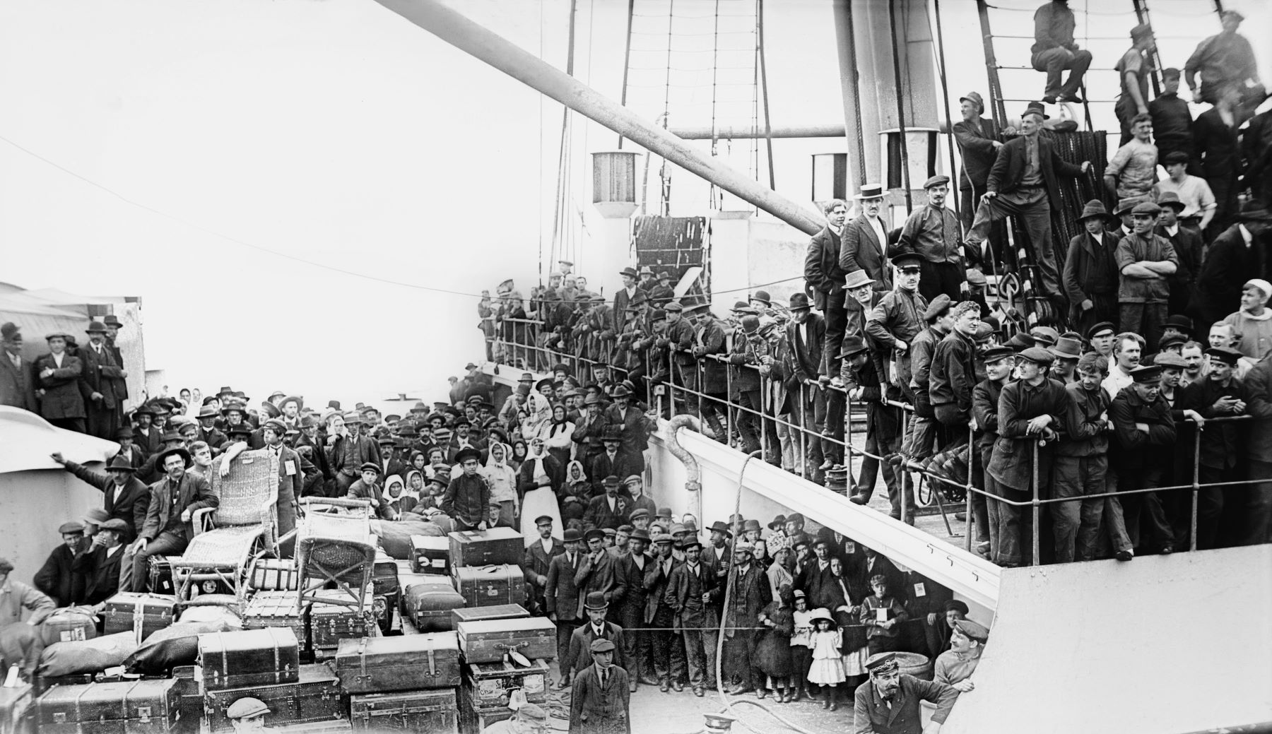 Black and white image of hundreds of immigrants packed onto deck of ship