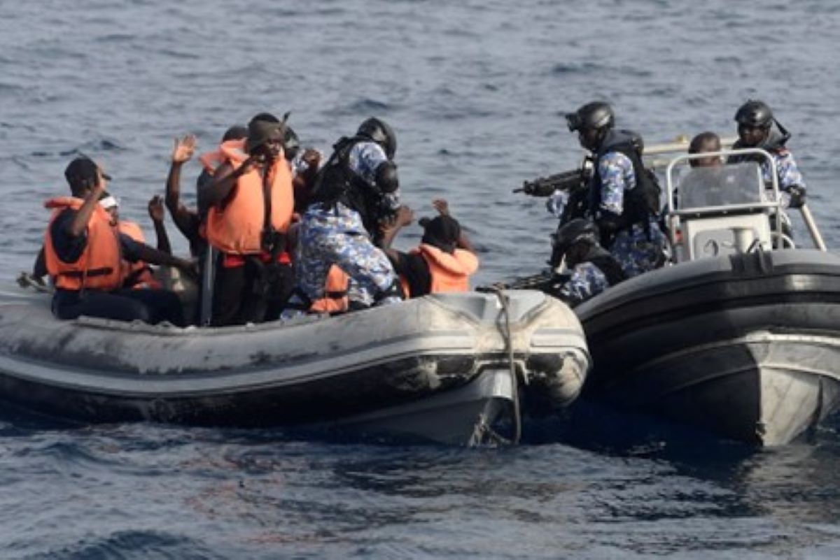Soldiers in small craft point guns at men in inflatable boar