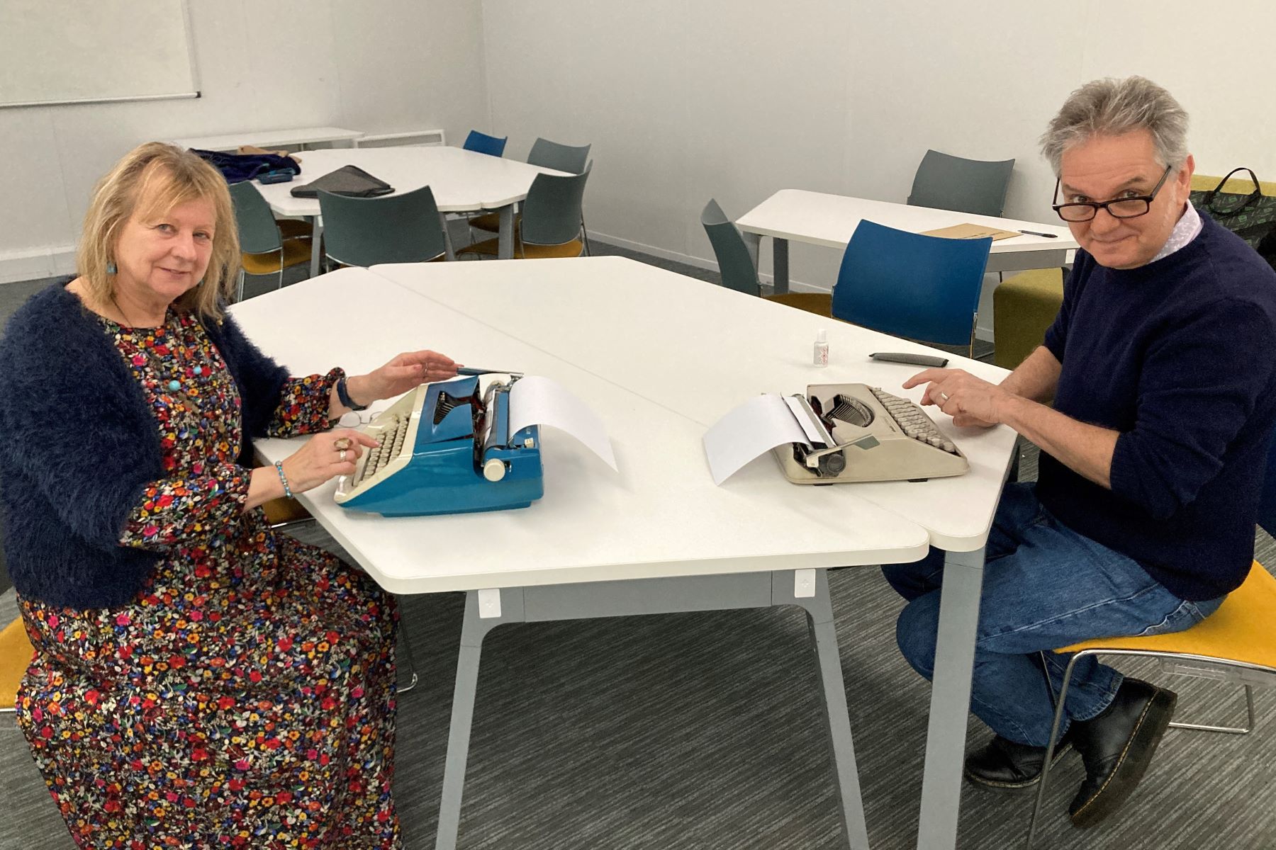 Woman and a man at typewriters facing each other across a desk