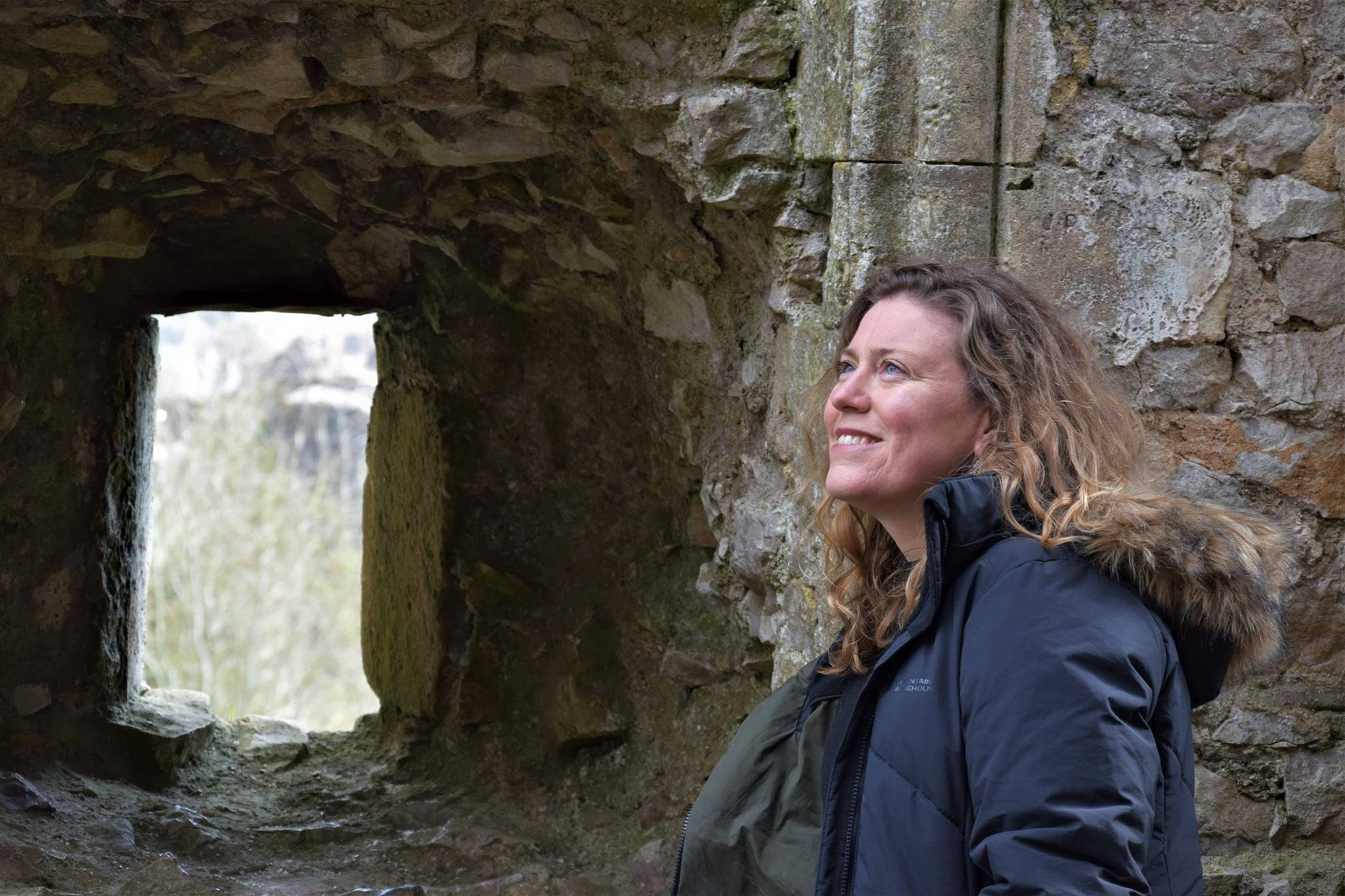 Woman standing in front of old stone walls and gateway