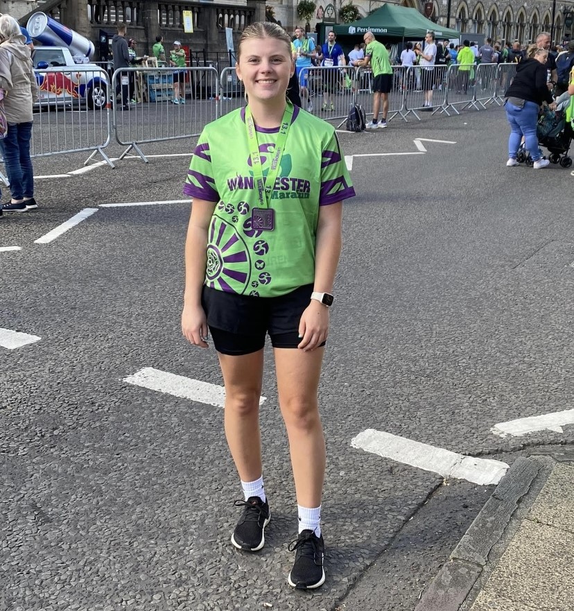 Young woman in running gear smiling with medal around neck