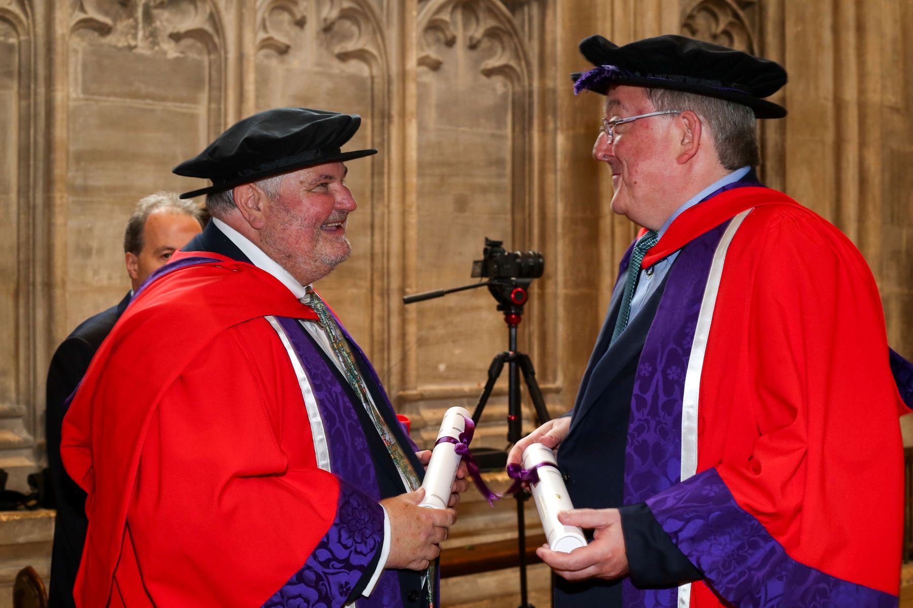 Two men in red academic robes facing each other