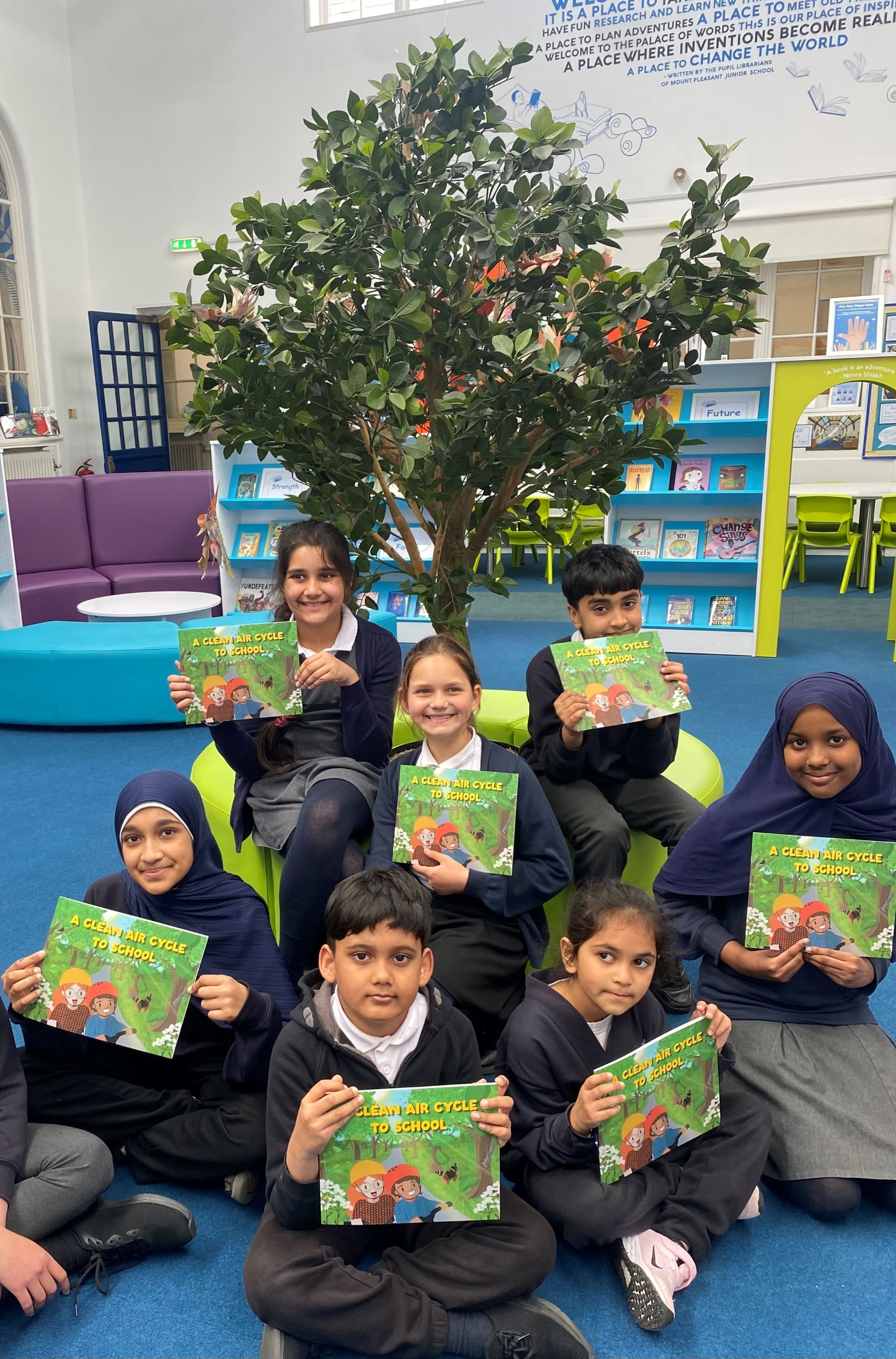 School pupils sat cross legged holding up copy of picture book