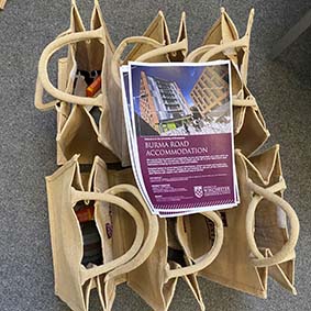 Three female staff with welcome bags standing outside halls of residence