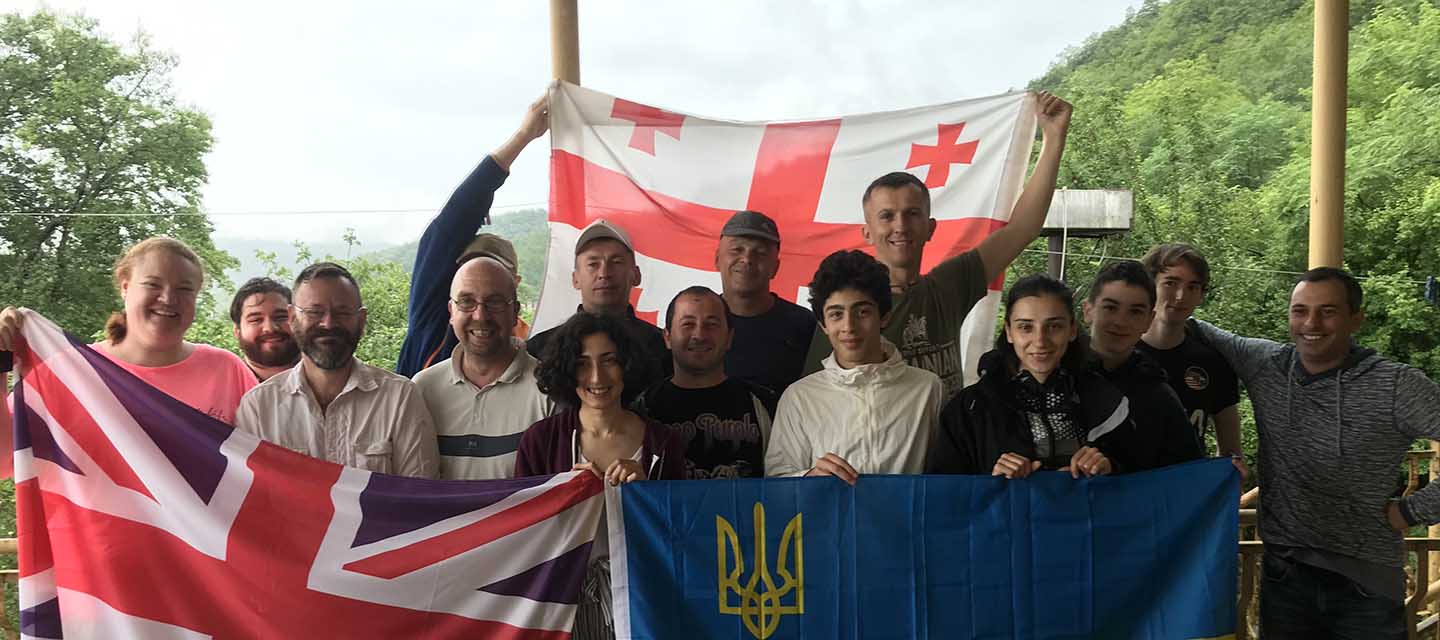 Group of men and women outside holding up national flags