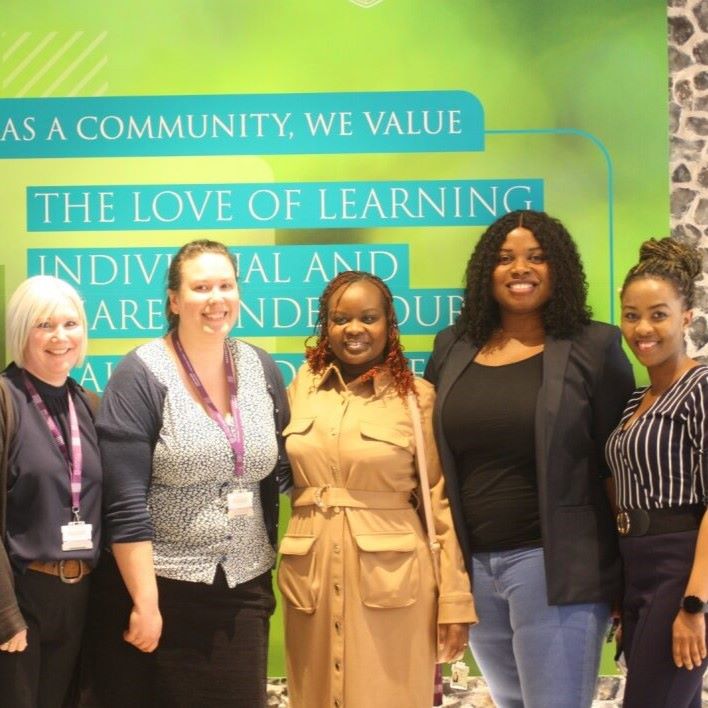 Five women in front of green university poster