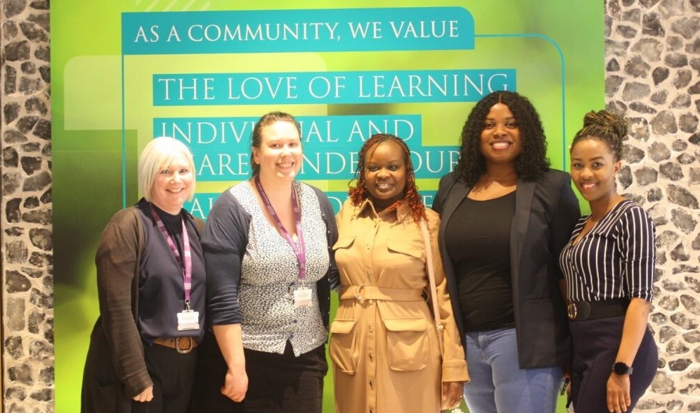 Five women in front of green university poster