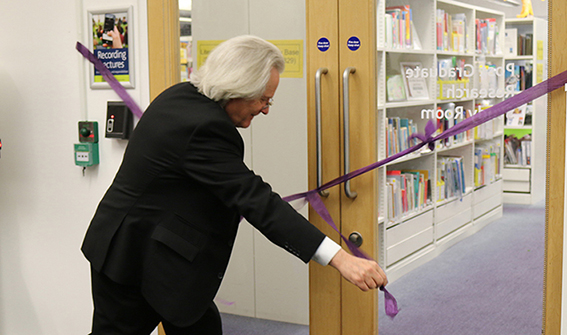 A C Grayling cutting a purple ribbon across glass double doors into the PGR study room