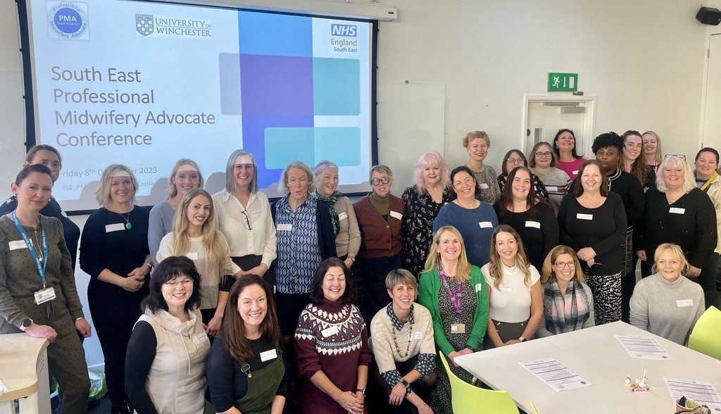 Group of women standing in front screen at conference