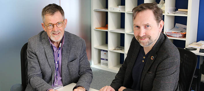 Signing ceremony with two men sitting at a desk