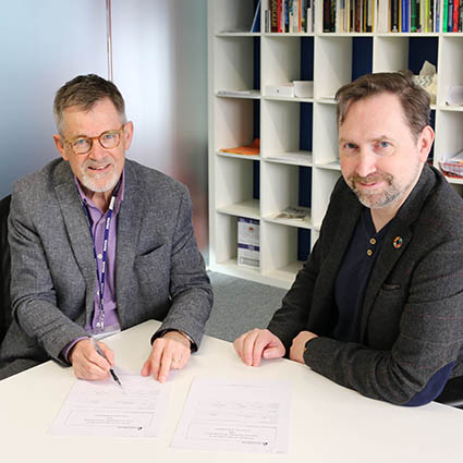 Signing ceremony with two men sitting at a desk