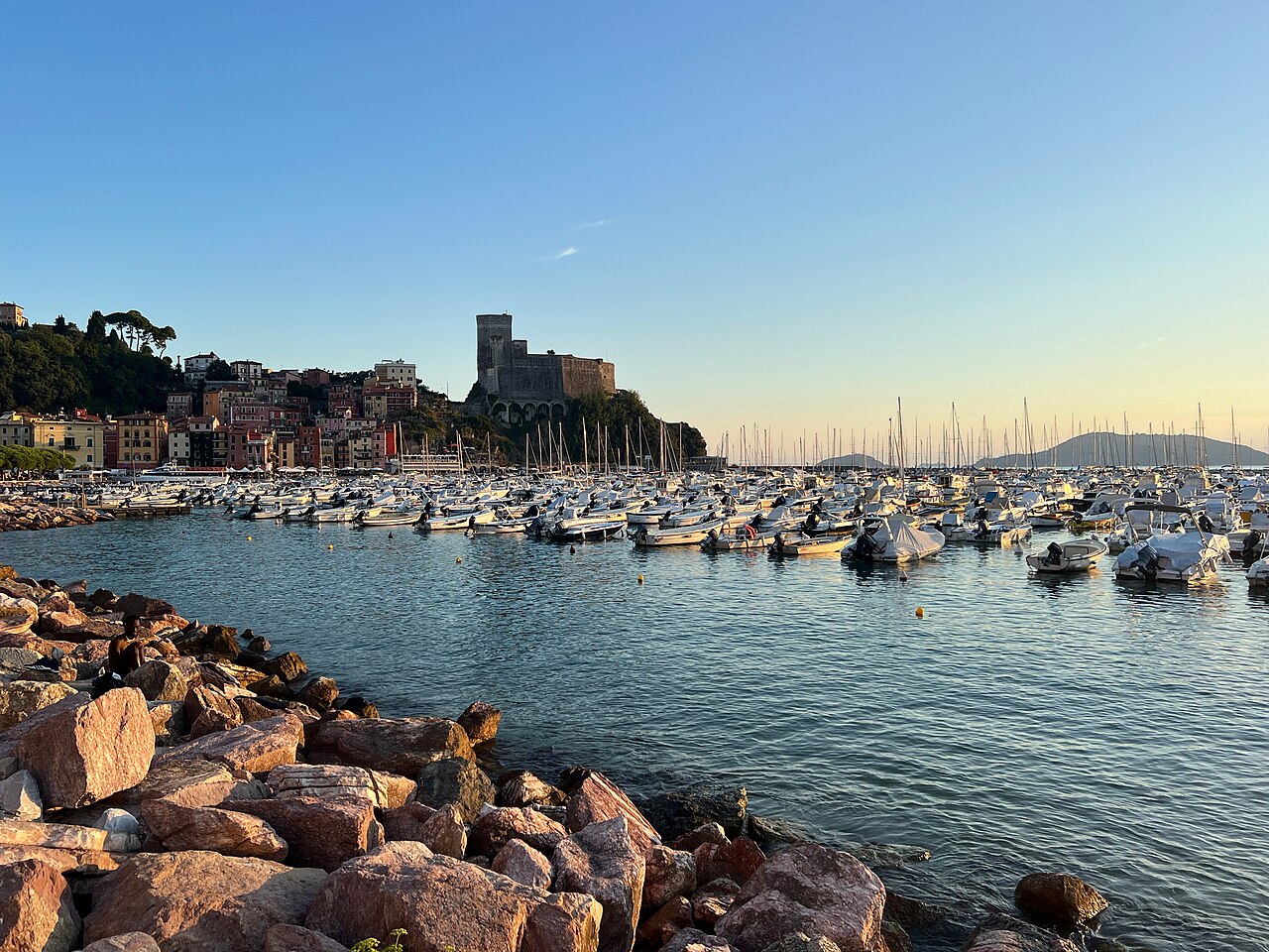 View across a sunlit bay with yacht to a castle on a rocky outcrop