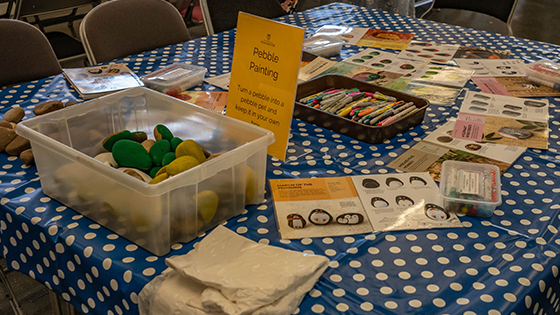 Table cvered with crayons and other equipment for painting pebbles